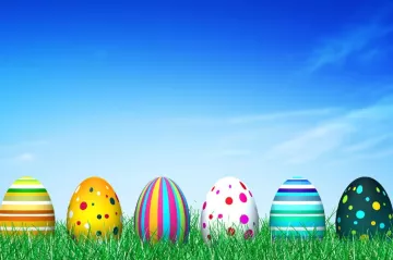 picture of Easter eggs on grass with the blue sky in the background 