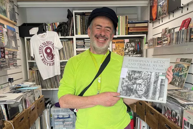 Simon, owner of Vinyl Vanguard, in the shop holding a record
