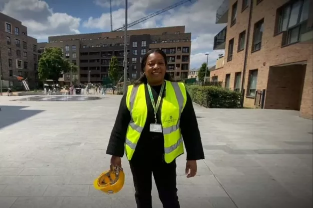 A person in high-vis standing in front fountains surrounded by flats