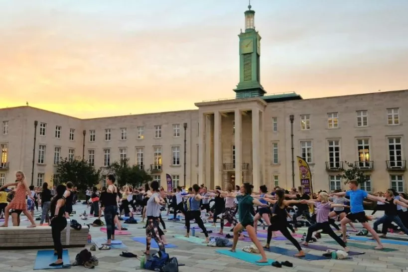 People doing yoga at Fellowship Square with arms outstretched.