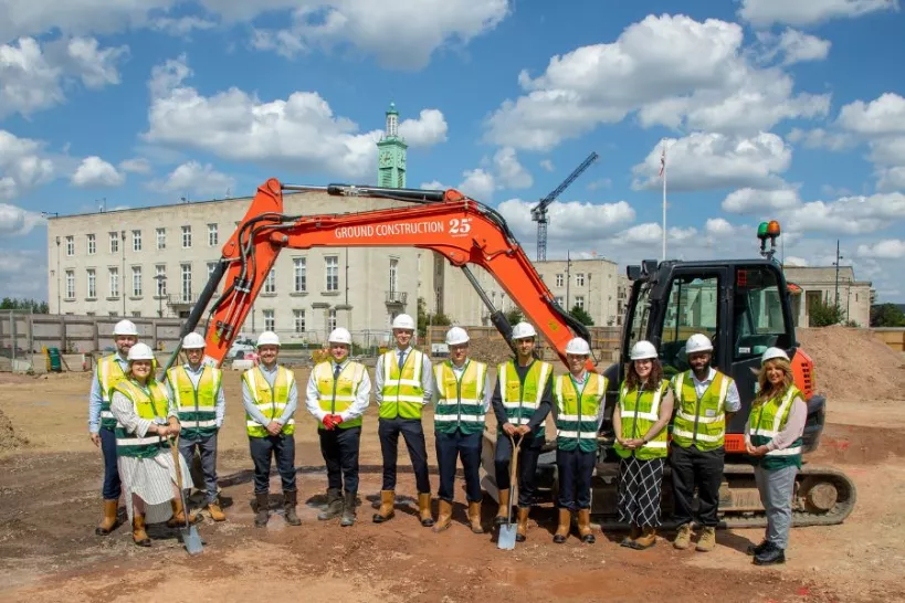 A group of people standing in front of a digger and Waltham Forest Town Hall